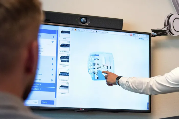 Adviseur wijst op een scherm met een 3D-ontwerp van een bedrijfswageninrichting met Sortimo-opbergsystemen